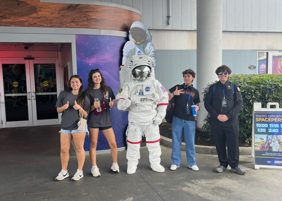 Club member Carson Broome along with alumni Isabella Suarez, Keegan Flury and Augustus Ettore pose beside an astronaut suit at Kennedy Space Center. 
Photo courtesy of Alyssa Bowman.