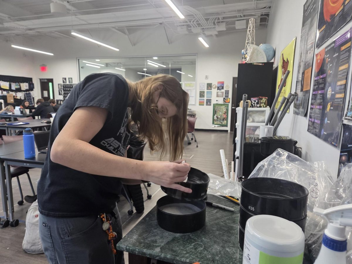 Junior Anson Books sifts martian soil for her AP Research data collection. Books’s project is focused on measuring and comparing the angle of repose, or steepness, of different types of soil grain, reflecting her interests in physics and space exploration.